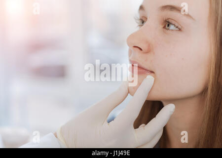 Proficient dermatologist examining patient face à la clinique Banque D'Images