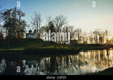 Bel après-midi la lumière en parc public avec l'herbe verte, l'Église orthodoxe de la Transfiguration du Christ et arbres se reflétant dans l'étang. Tourné à Cesis, la Lettonie. Banque D'Images