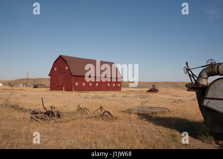 1928 partiellement restauré sur la grange Joe Hartman Ranch. La herse à l'abandon et de la moissonneuse-batteuse fournir framing de ce premier plan est du Montana photo. Banque D'Images