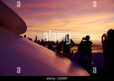 Les touristes de prendre des photos de l'horizon de Chicago sur la croisière au coucher du soleil. Plusieurs personnes à l'aide de téléphones cellulaires de la coucher de soleil rose. Les gens sont en silhouette. Banque D'Images