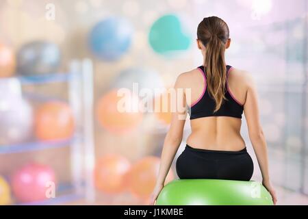 Digital composite of Rear view of woman sitting on fitness ball at gym Banque D'Images