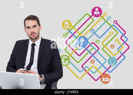 Digital composite de Portrait of businessman using laptop avec des icônes en arrière-plan Banque D'Images