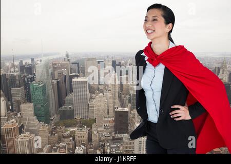 Digital composite of Happy businesswoman en costume de super héros au-dessus de ville Banque D'Images