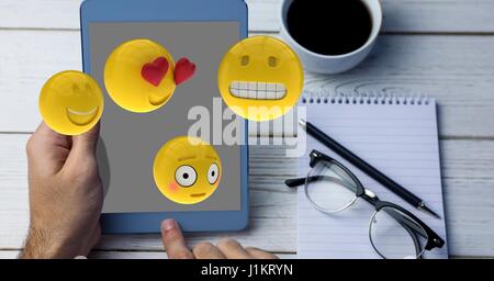 Digital composite de close-up de mains à l'aide de Tablet PC et émoticônes survolant le tableau Banque D'Images