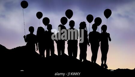 Digital composite de Silhouette les enfants avec des ballons sur hill against sky Banque D'Images