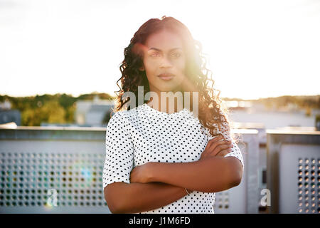 Portrait d'une femme afro-américaine pose pour appareil photo avec les bras croisés Banque D'Images