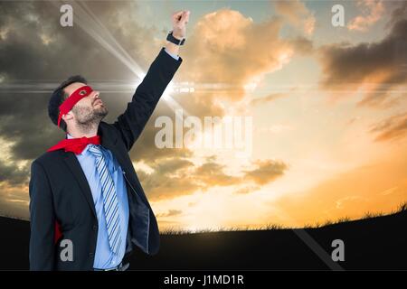 Digital composite de l'homme d'affaires en costume de super-héros avec la main posée contre le ciel Banque D'Images