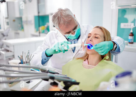 L'utilisation d'instruments d'éclairage dentaire dentiste pour travailler avec les dents Banque D'Images