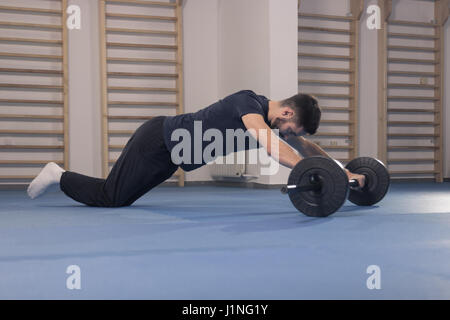 Seulement, un jeune homme maigre exercice SLIM, un haltère, à l'intérieur, étage bar poids d'haltères, abs Ab Mise en place. Banque D'Images