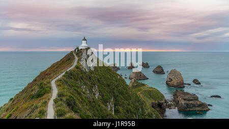 Le lever du soleil, au phare, le Nugget Point, Catlins, Région de l'Otago Southland, Nouvelle-Zélande Banque D'Images