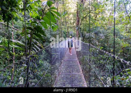 Femme marche sur le pont suspendu, rainforest, ponts suspendus d'Arenal Mistico, Parc National du Volcan Arenal Banque D'Images