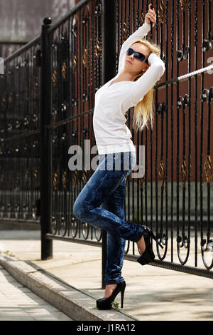 Blond woman at the cast iron fence Banque D'Images