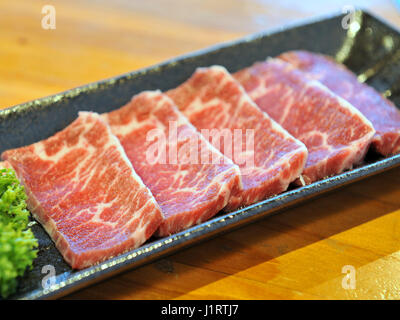 Tranches de boeuf cru frais sur plateau noir