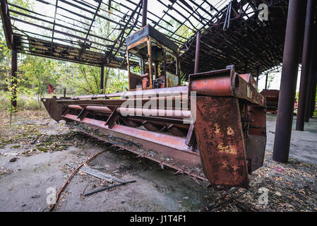 Ancienne station de moissonneuse-batteuse dans des machines agricoles de l'abandon des kolkhoz près de Zymovyshche village dans la zone d'aliénation de Tchernobyl, l'Ukraine Banque D'Images