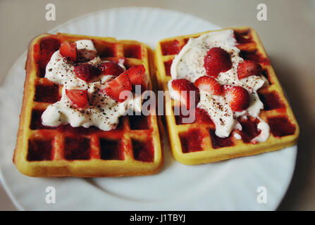 De délicieuses gaufres maison avec de la crème chantilly, de la confiture, du cacao et des fraises. Banque D'Images