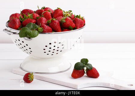 Rip frais fraises dans un bol sur la table en bois blanc Banque D'Images