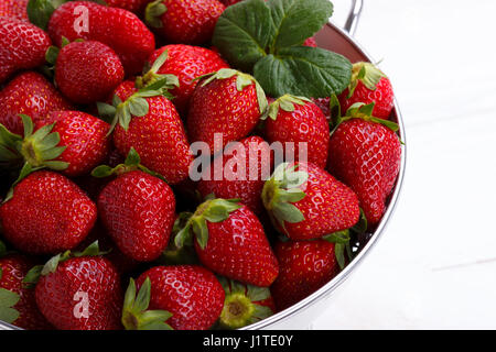 Rip frais fraises dans un bol sur la table en bois blanc Banque D'Images