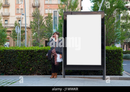 Woman with mobile phone, debout dans un blank billboard Banque D'Images