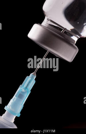Medical seringue avec l'aiguille dans la fiole. Isolé sur fond noir Banque D'Images