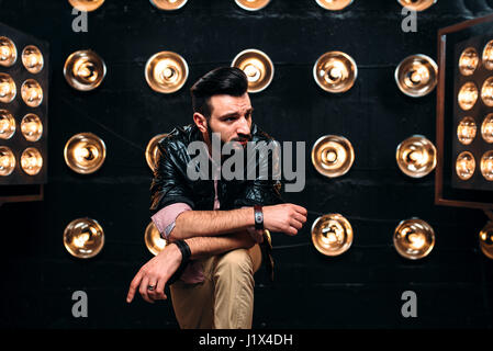 Chanteur barbu en veste en cuir noire sur la scène avec les décors de lumières Banque D'Images