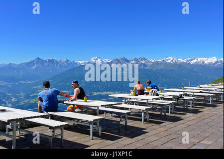 Quatre personnes assises sur des bancs en bois dans le restaurant en plein air et admirer la vue panoramique de la station de téléphérique Seegrube Banque D'Images