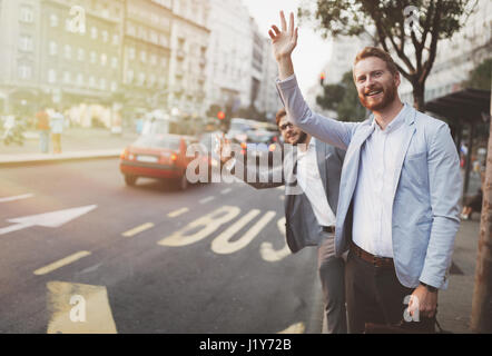 Businessman waving pour un taxi en ville animée Banque D'Images