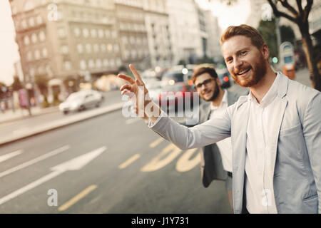 Businessman waving pour un taxi en ville animée Banque D'Images