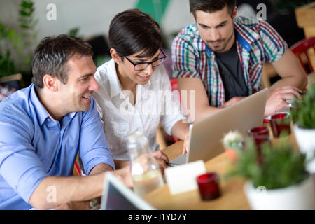 Happy young business people working on laptop shop dans le café Banque D'Images