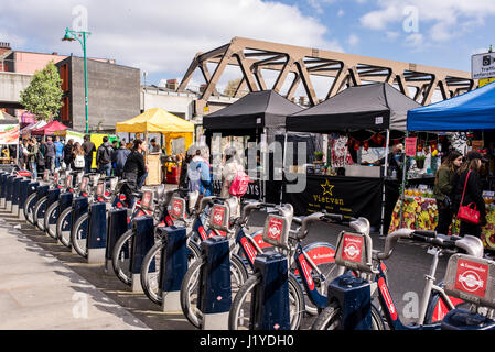 Street View de Brick Lane Market avec des gens et des stands de nourriture à côté d'un des cycles de Santander station d'accueil. Brick Lane, Shoreditch, London, UK Banque D'Images