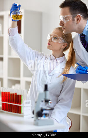 Les élèves font des recherches en laboratoire d'expérimentation chimique holding flask Banque D'Images