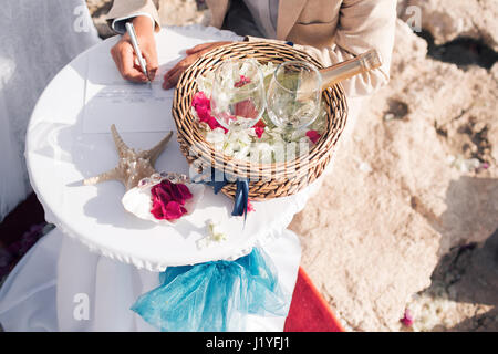 Le marié met sa signature. mariage à Chypre, de l'époux et l'épouse sur un pont de pierre à Agia Napa. arch et table pour l'enregistrement du mariage. La vue sur la mer. Sur la côte de la roche Banque D'Images