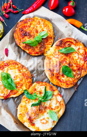 Mini pizzas bruschettas ou avec du fromage, salami et feuilles d'épinards frais,vue d'en haut Banque D'Images