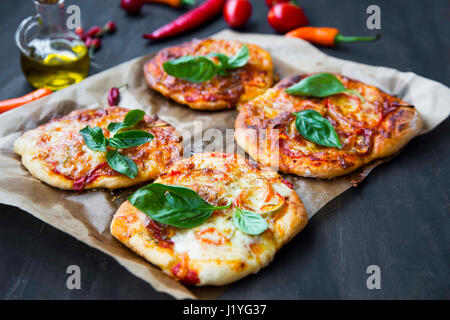 Mini pizzas bruschettas ou avec du fromage, salami et feuilles d'épinards frais,vue d'en haut Banque D'Images