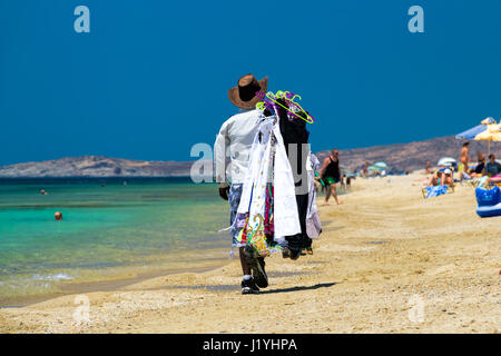 Vendeur sur la plage - vue arrière d'un homme marchant le long de la plage portant des vêtements, de Maragas (Plaka), l'île de Naxos, Cyclades, Grèce Banque D'Images