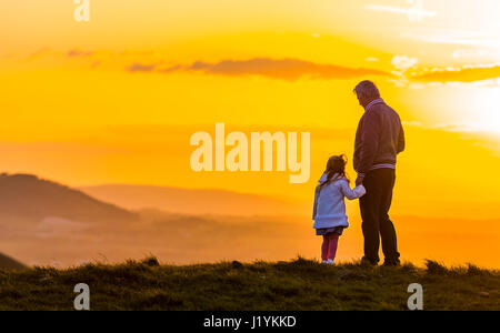 Relation Père fille. Père et fille se tenant ensemble se tenant la main sur une colline, jouissant de regarder le soleil se coucher. Banque D'Images