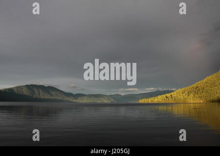 Beaux paysages de l'Altaï lac Teletskoye au coucher du soleil avec des nuages sombres couverts le ciel Banque D'Images