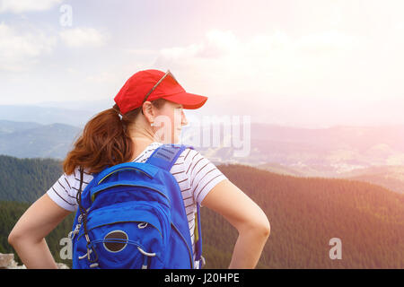 Jeune femme avec sac à dos bleu enjoying view à partir du haut de la montagne Banque D'Images