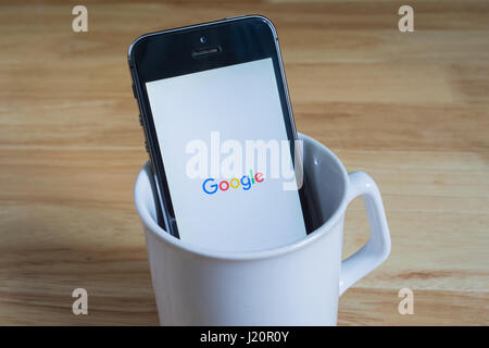 Bangkok, Thaïlande - 22 Avril 2017 : Apple iPhone5s dans un mug montrant l'écran avec logo Google. Banque D'Images