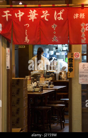 Tokyo, Japon - 22 juin 2016 : serveuse et cuisinier de compensation sont une rue animée restaurant à la fin de la soirée. Banque D'Images