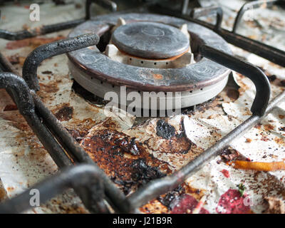 La sale et crasseux et Rusted Haut de cuisinière à gaz plaque de cuisson avec des morceaux de papier aluminium sous la tôle avec des morceaux de nourriture et des Detaul brillant avec les fissures et Banque D'Images