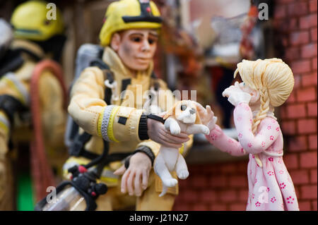 Alexandra Palace, au Royaume-Uni. 23 avril, 2017. Fait main unique et intéressant des gâteaux sur l'affichage à l'International à gâteau Alexandra Palace, Londres. Les concurrents de partout dans le monde est venu pour concurrencer dans le plus grand concours de gâteau. Plusieurs prix ont été remis aux participants des amateurs pour les profesionnels. Il y a différentes catégories d'entrer avec les règles établies pour chaque catégorie, ce qui a donné lieu à des dessins pour chaque gâteau. Close-up d'un gâteau qui ressemble à une petite statue et non un gâteau. La scène est d'une maison en feu et un pompier de remettre un chiot sauvé à une fille pleurer. Andrew Steve Banque D'Images