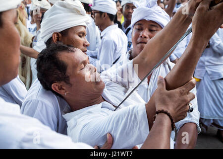 Kesiman, Denpasar, Bali, Indonésie. Apr 23, 2017. Homme balinais dans une transe tente de percer sa peau avec un traditionnel Keris (couteau) au cours de l'auto de poignard rituel de Sakral au Pengerebongan cérémonie. Ce rituel a lieu tous les 210 jours sur le calendrier Saka hindous balinais et est un test solennelle des dévots foi en Dieu ! Temple Pura Petilan, Denpasar, Indonésie. Crédit : Antony Ratcliffe/Alamy Live News. Banque D'Images