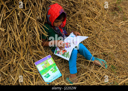 L'école primaire un élève lit un livre qu'elle a ses nouveaux manuels pour nouvelle classe à Singair. Manikganj, Bangladesh Banque D'Images