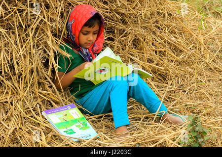 L'école primaire un élève lit un livre qu'elle a ses nouveaux manuels pour nouvelle classe à Singair. Manikganj, Bangladesh Banque D'Images