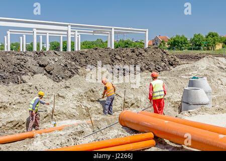 Organisé dans les conduites d'eau en PVC sont assemblés et placés dans la tranchée sur chantier. Banque D'Images