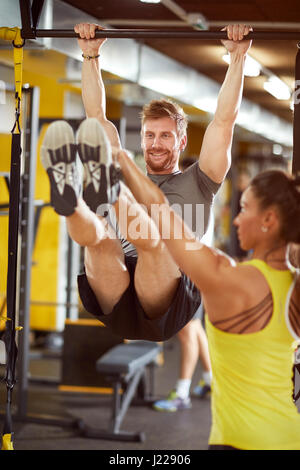 Homme avec femme instructeur dans la salle de sport sur l'équipement d'exercice Banque D'Images