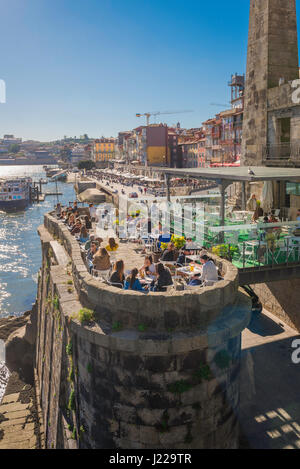 Cafe Ribeira Porto, les touristes assis à une terrasse de café construit sur une pierre jetée une fois partie de l'original bridge le long de la Cais da Ribeira à Porto. Banque D'Images