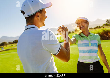 Heureux les amis masculins et féminins shaking hands at golf après le match. Golfeur Pro profiter de la partie sur le terrain. Banque D'Images