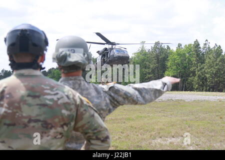 Un soldat avec l'École d'assaut aérien DeGlopper, XVIII Airborne Corps guides dans un UH-60 Black Hawk affecté à la 2ème bataillon d'hélicoptères d'assaut, 82e Brigade d'aviation de combat qu'elle prépare pour connecter un remorque cargo charge sous élingue sur Fort Bragg, N.C., 20 avril. (U.S. Photo de l'armée par le Sgt. Steven Galimore) Banque D'Images