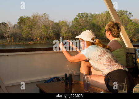 Les femmes photographier les animaux à terre, sur une croisière au coucher du soleil sur le Zambèze, le Zimbabwe, l'Afrique Banque D'Images